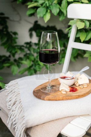 Photo for Glass of red wine with camembert on a chair in the garden. - Royalty Free Image