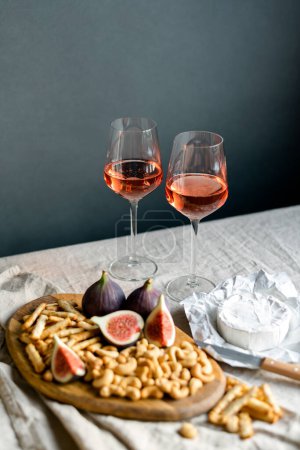 Téléchargez les photos : Vin rose aux figues mûres, fromage camembert et noix de cajou sur une table à l'intérieur. - en image libre de droit
