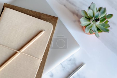 Photo for Desk scene of notebooks, laptop, pen, pencil, and succulent on marble background. - Royalty Free Image