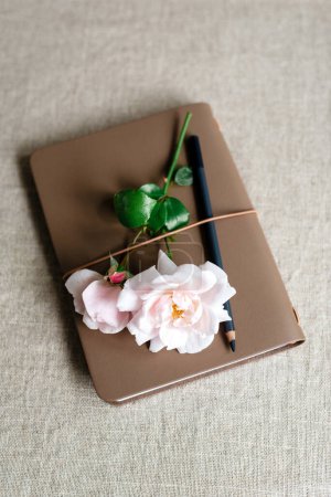 Photo for A garden rose lies on a notepad. - Royalty Free Image