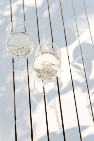 Foto de Dos copas de vino blanco en una mesa blanca al aire libre. - Imagen libre de derechos
