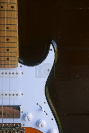 Photo for An electric guitar with a charming design sits in front of a dark brown wooden background - Royalty Free Image