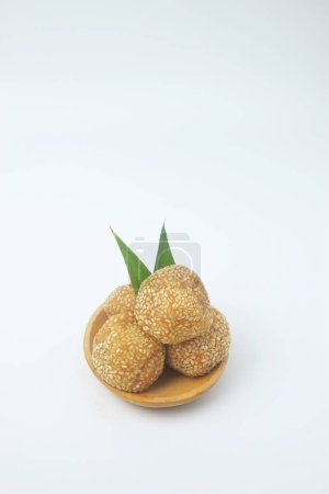 Portrait photo of a snack that has a golden round shape sprinkled with sesame seeds. In Indonesia it is often called Onde Onde. Isolated White