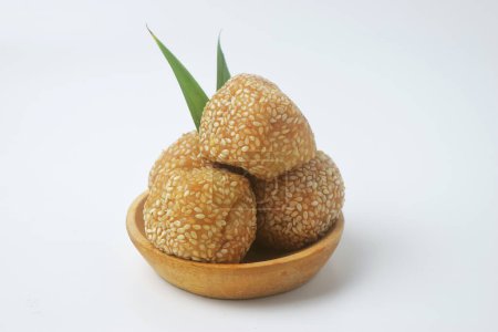A close up shot of a snack that has a golden round shape sprinkled with sesame seeds. In Indonesia it is often called Onde Onde. Isolated White