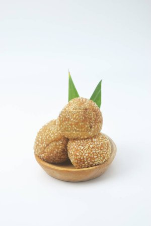 A close up shot of a snack that has a golden round shape sprinkled with sesame seeds. In Indonesia it is often called Onde Onde. Isolated White