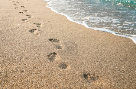 Photo for Beach, wave and footprints during the day. Texture background Footprints of human feet on the sand near the water on the beach. - Royalty Free Image