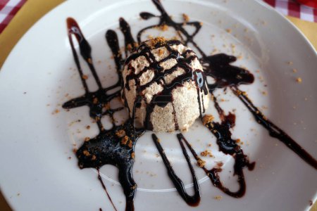 Photo for Milk ice cream scoop covered with chocolate sauce on plate with condiments in restaurant - Royalty Free Image
