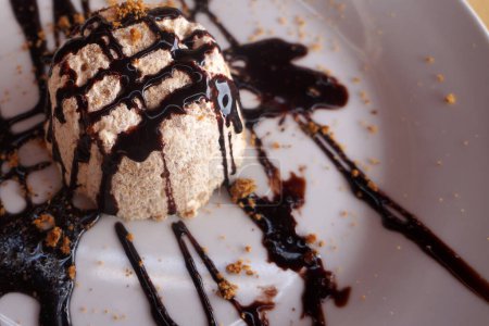 Téléchargez les photos : Cuillère à crème glacée au lait recouverte de sauce au chocolat sur assiette avec condiments au restaurant - en image libre de droit