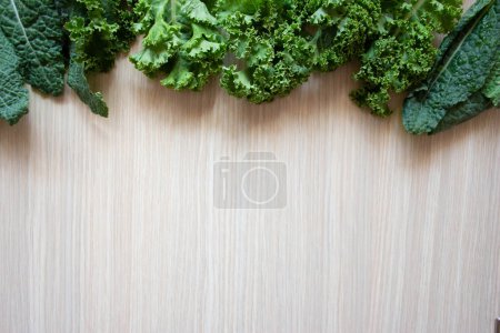 Photo for Organic curly kale leaves mix on a light wooden table, top view with space for text - Royalty Free Image
