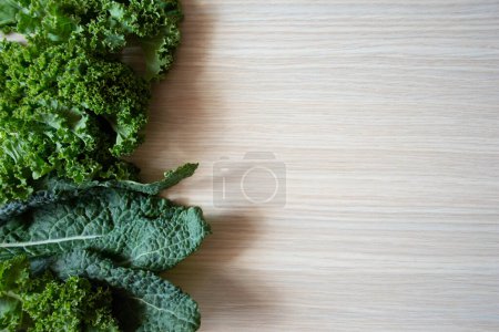 Photo for Organic curly kale leaves mix on a light wooden table, top view with space for text - Royalty Free Image
