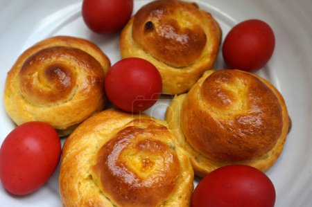 Foto de Pan de pan de Pascua y huevos rojos en un tazón. Comida tradicional rumana. Pan dulce rumano bollo - Imagen libre de derechos