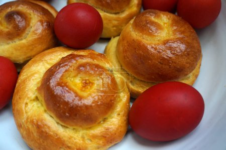 Foto de Pan de pan de Pascua y huevos rojos en un tazón. Comida tradicional rumana. Pan dulce rumano bollo - Imagen libre de derechos