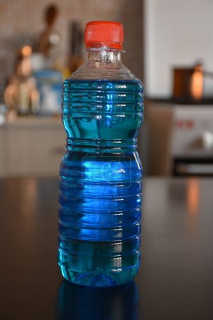 Photo for Sanitary alcohol bottle on a wooden table. Blue rubbing alcohol bottle - Royalty Free Image