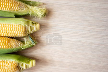 Photo for Organic corn cobs on wood background. Grains of ripe corn on light wooden background. - Royalty Free Image