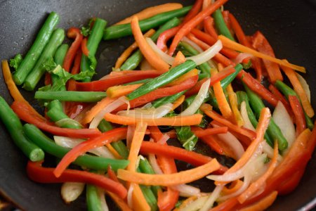 Téléchargez les photos : Mélanger les légumes frits dans une poêle à la maison. Mélanger divers légumes dans une casserole. Photo de haute qualité - en image libre de droit