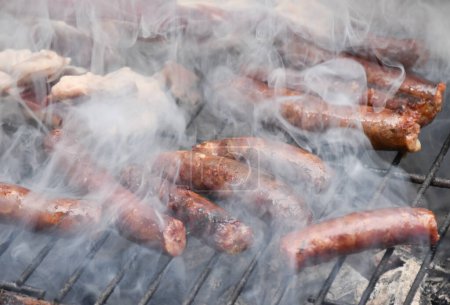 Photo for Sausages on a smoking grill, close-up. Sausage BBQ on wood ember, smoking. Barbecue, smoke background. High quality photo - Royalty Free Image