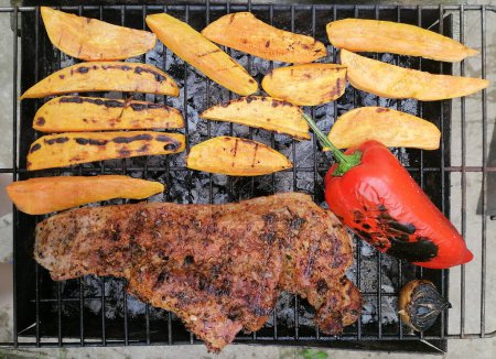 Photo for Close up of an grill with meat and sweet potatoes at barbecue session. Picnic outdoors lunch concept on spring summer time - Royalty Free Image