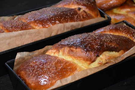 Téléchargez les photos : Pain roumain sucré aux noix. Cozonac, traditionnel gâteau roumain en éponge. Pain sucré de Noël et de Pâques dans des plateaux sur un fond en bois noir - en image libre de droit