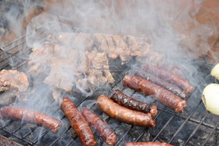Photo for Sausages on a smoking grill, close-up. Sausage BBQ on wood ember, smoking. Barbecue, smoke background. High quality photo - Royalty Free Image