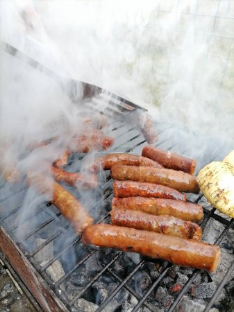 Photo for Man turns sausages on a smoking grill with a fork. Sausages BBQ smoking. High quality photo - Royalty Free Image