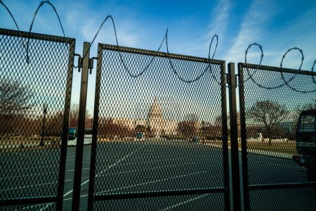 Téléchargez les photos : Le bâtiment du Capitole américain au coucher du soleil, fortifié derrière une clôture métallique surmontée d'un fil de rasoir pour répondre aux préoccupations de sécurité dans les mois qui ont suivi l'insurrection du 6 janvier 2021. Washington, DC. - en image libre de droit