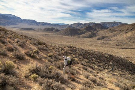 Téléchargez les photos : Deux routards mâles montent une colline, qui fait partie du populaire sentier de randonnée en boucle Cottonwood Canyon-Marble Canyon dans le parc national Death Valley en Californie. - en image libre de droit