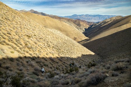 Téléchargez les photos : Quatre randonneurs masculins descendent dans le canyon Deadhorse, qui fait partie du populaire sentier de randonnée en boucle Cottonwood Canyon-Marble Canyon dans le parc national Death Valley en Californie. - en image libre de droit