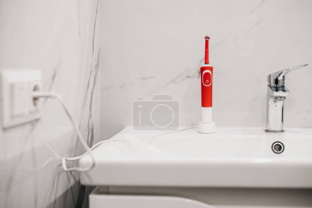 Foto de Cepillo de dientes eléctrico en el cargador en el baño - Imagen libre de derechos