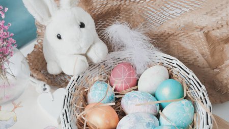 Huevos de Pascua en una cesta y conejo de juguete. .. Composición de Pascua. Concepto de vacaciones. Foto de alta calidad.