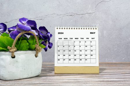 Weißer Kalender Mai 2024 auf Bürotisch aus Holz mit Topfpflanze. Neujahrskonzept 2024