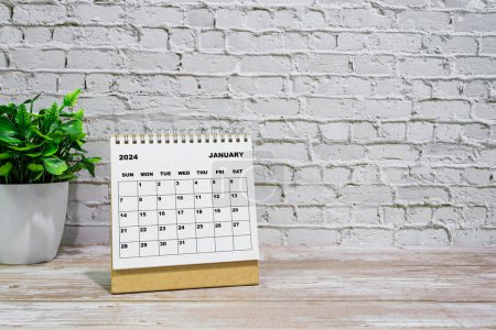 Weißer Januar 2024 Kalender auf Bürotisch aus Holz mit Topfpflanze. Neujahrskonzept 2024