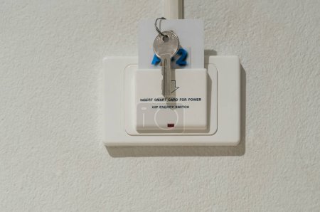 Foto de Smart card with key is inserted into white socket with text reading Insert smart card for power installed on white wall in luxurious hotel or resort room. - Imagen libre de derechos
