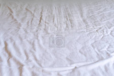 Crumpled or wrinkled white bedding sheet background texture was taken with soft natural light used for clothing background texture.