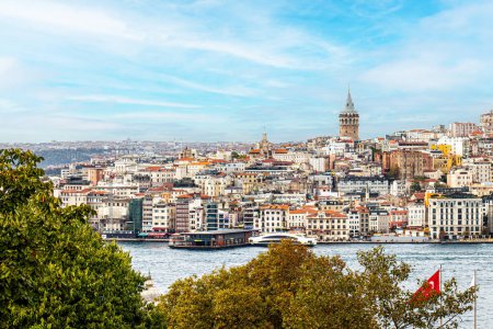 Photo for The Galata Tower looms over the dense, colorful buildings of Istanbul's skyline, with the bustling Bosphorus in the foreground, encapsulating the city's vibrant urban life. - Royalty Free Image