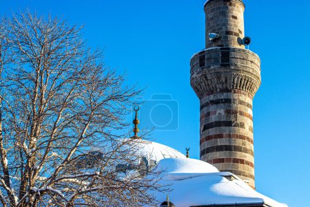 Scène hivernale de la mosquée Lalapasa à Erzurum avec dôme enneigé et minaret.