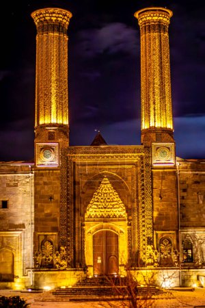 beleuchtete Zwillingsminarette des historischen Minaretts Cifte Minareli Medrese bei Nacht oder Twin Minaret Madrasa. Hochwertiges Foto
