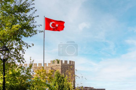 Erzurum Kalesi or Turkish flag flying proudly above Erzurum Castle under a clear sky.
