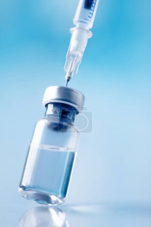 Téléchargez les photos : Glass vial and syringe with injection over blue background. Vaccination or beauty therapy concept. - en image libre de droit