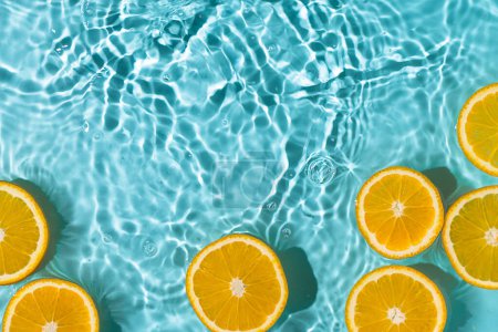 Téléchargez les photos : Fond d'été créatif avec des tranches de fruits d'orange dans l'eau de la piscine. Papier peint d'été avec espace de copie. - en image libre de droit