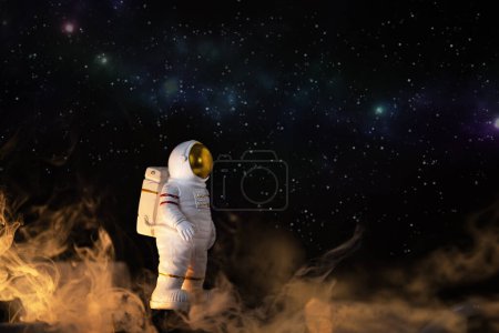 Figur des Astronauten über blauem Sternenhimmel, Kopie des Weltraums. Spielzeug des Raumfahrers. Raumfahrt- und Raumfahrtkonzept. Tag der Kosmonauten.