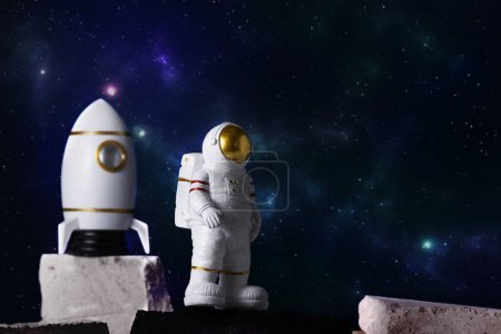 Figurine of astronaut and rocket over sky background, copy space. Toy of spaceman and cosmos shuttle. Space and space flights concept. Day of cosmonauts.