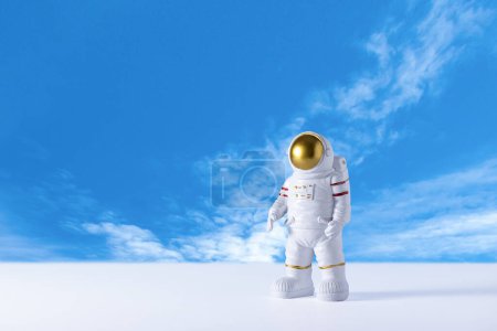Figur des Astronauten über blauem Himmelshintergrund, Kopie des Weltraums. Spielzeug des Raumfahrers. Raumfahrt- und Raumfahrtkonzept. Tag der Kosmonauten.