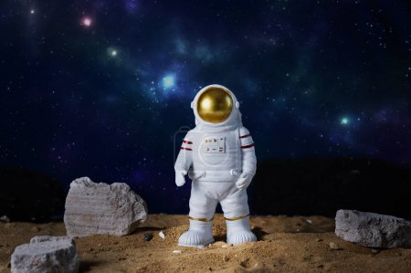 Foto de Figura de astronauta sobre fondo azul del cielo estrellado, espacio de copia. Juguete del astronauta. Concepto de vuelos espaciales y espaciales. El día de los cosmonautas. - Imagen libre de derechos