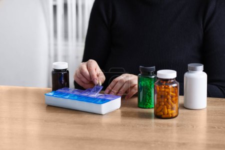 Mujer poniendo píldoras recetadas y vitaminas en una píldora diaria organizador. Clasificación de suplementos nutricionales y antibióticos en el envase de pastillas semanales.