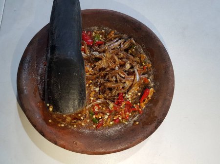 Hot spicy sauce from chilli peppers, shallots, garlic, various spices and tomatoes in bowl on wooden table. red hot sweet chilli sauce over old wooden background.