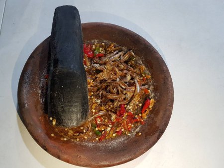 Hot spicy sauce from chilli peppers, shallots, garlic, various spices and tomatoes in bowl on wooden table. red hot sweet chilli sauce over old wooden background.