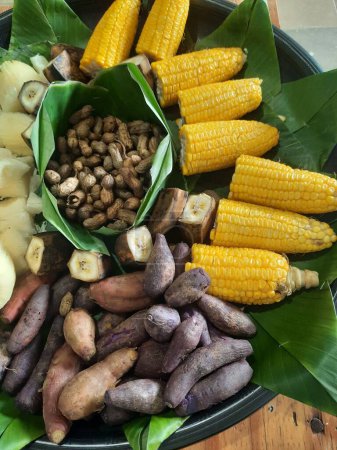 Délicieux plats traditionnels indonésiens tels que bananes, manioc, patates douces, cacahuètes, maïs bouilli est servi avec des tampons de feuilles de banane sur un plateau en bambou tissé