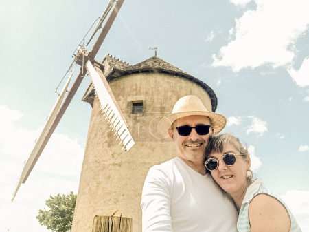 Retrato de una pareja de vacaciones con un molino de viento en el fondo.