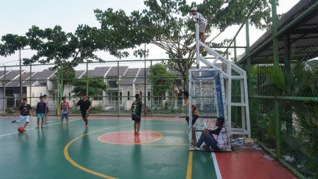 Téléchargez les photos : Surabaya, East Java, Indonesia - January, 2023 : the children spent the afternoon barefoot playing soccer on the futsal cement field near the house - en image libre de droit