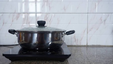 Photo for Electric stove with a boiling pot on a ceramic background in the kitchen - Royalty Free Image